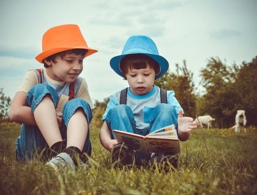 Deux enfants lisent un livre sur l'herbe