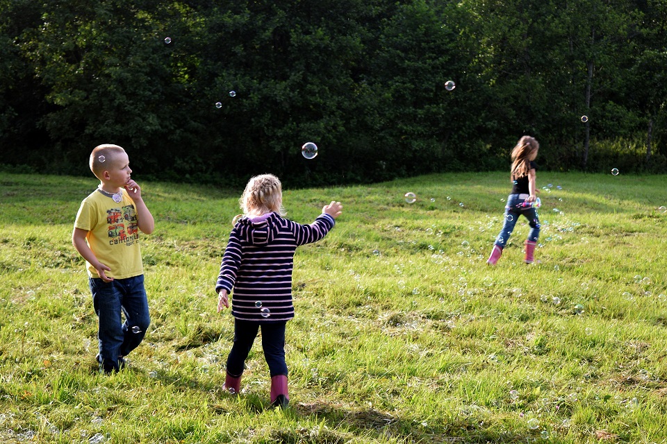 Garçon qui joue aux bulles avec deux filles