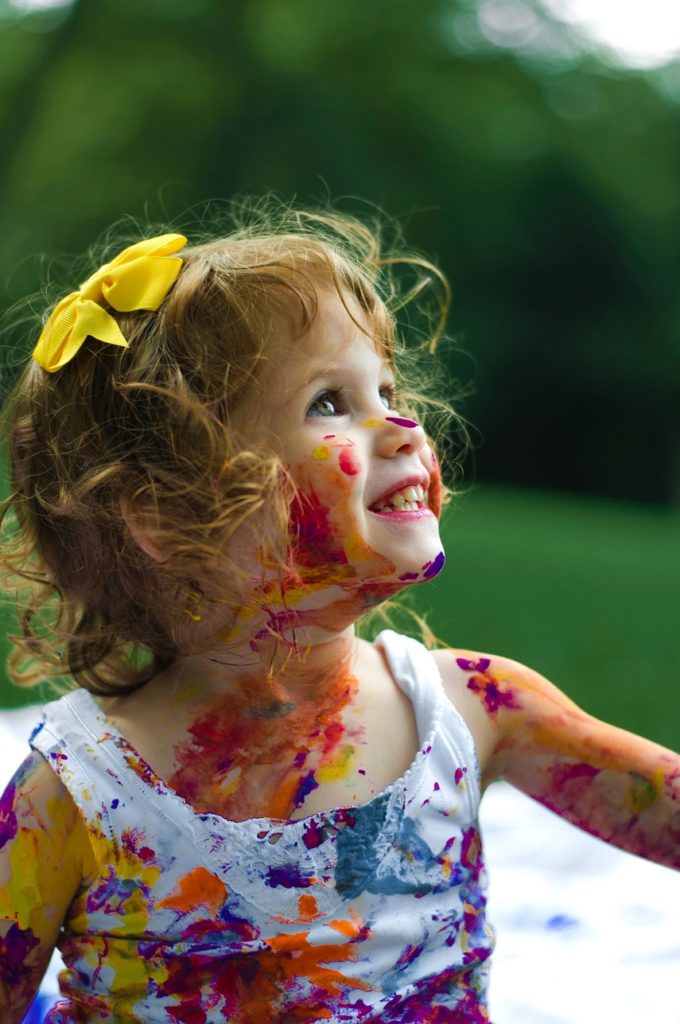 Une petite fille recouverte de peinture sourit