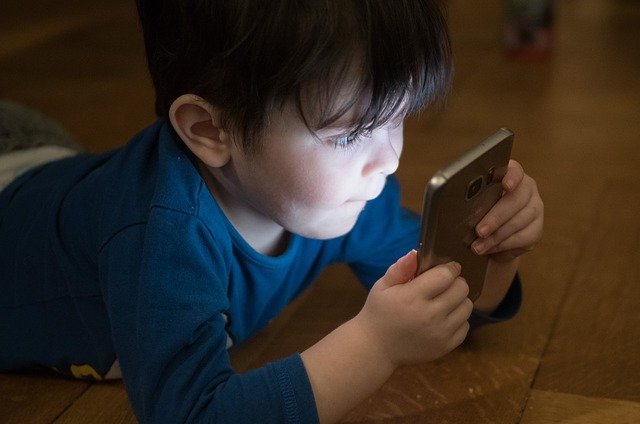 Un petit garçon regarde un téléphone portable