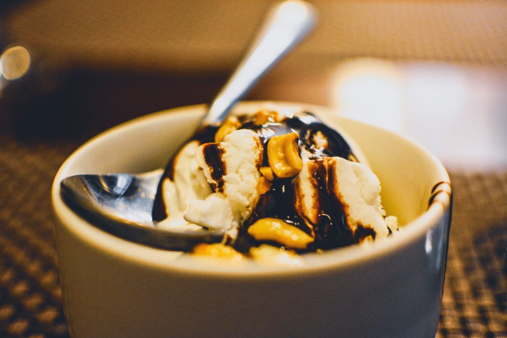 crème glacée avec cacahuètes et nappage chocolat dans un bol avec cuillère 