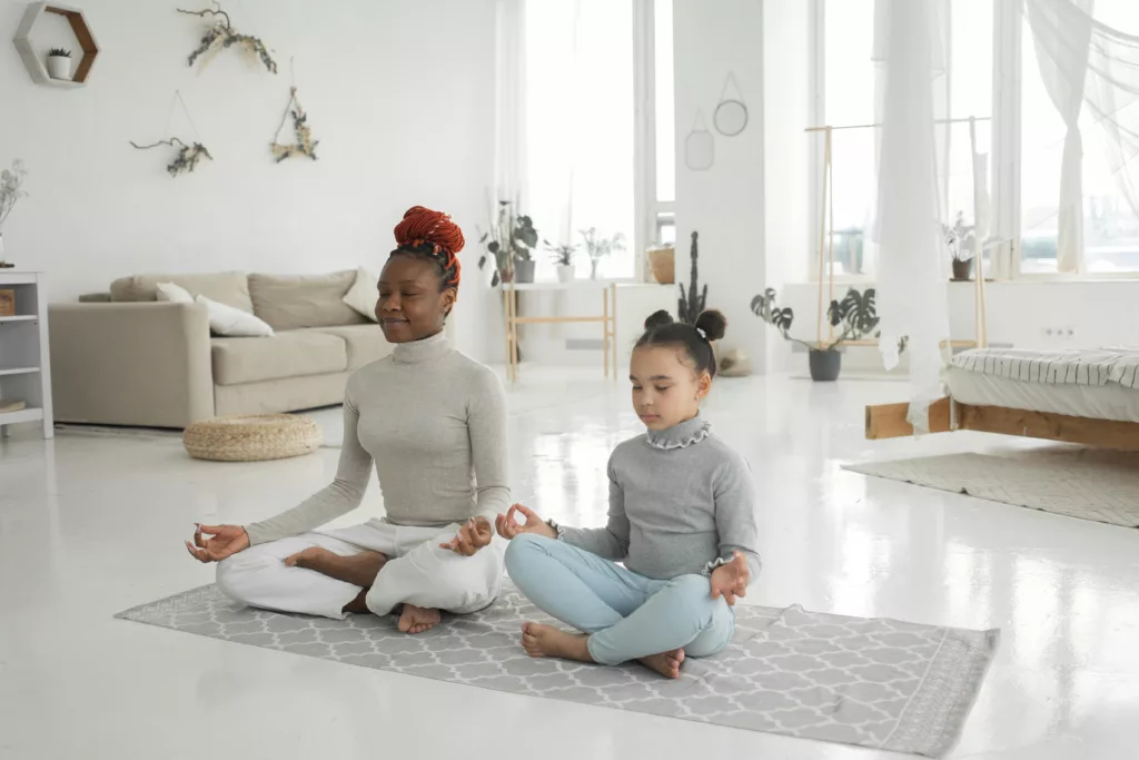 Un adulte et une enfant méditent dans leur salon