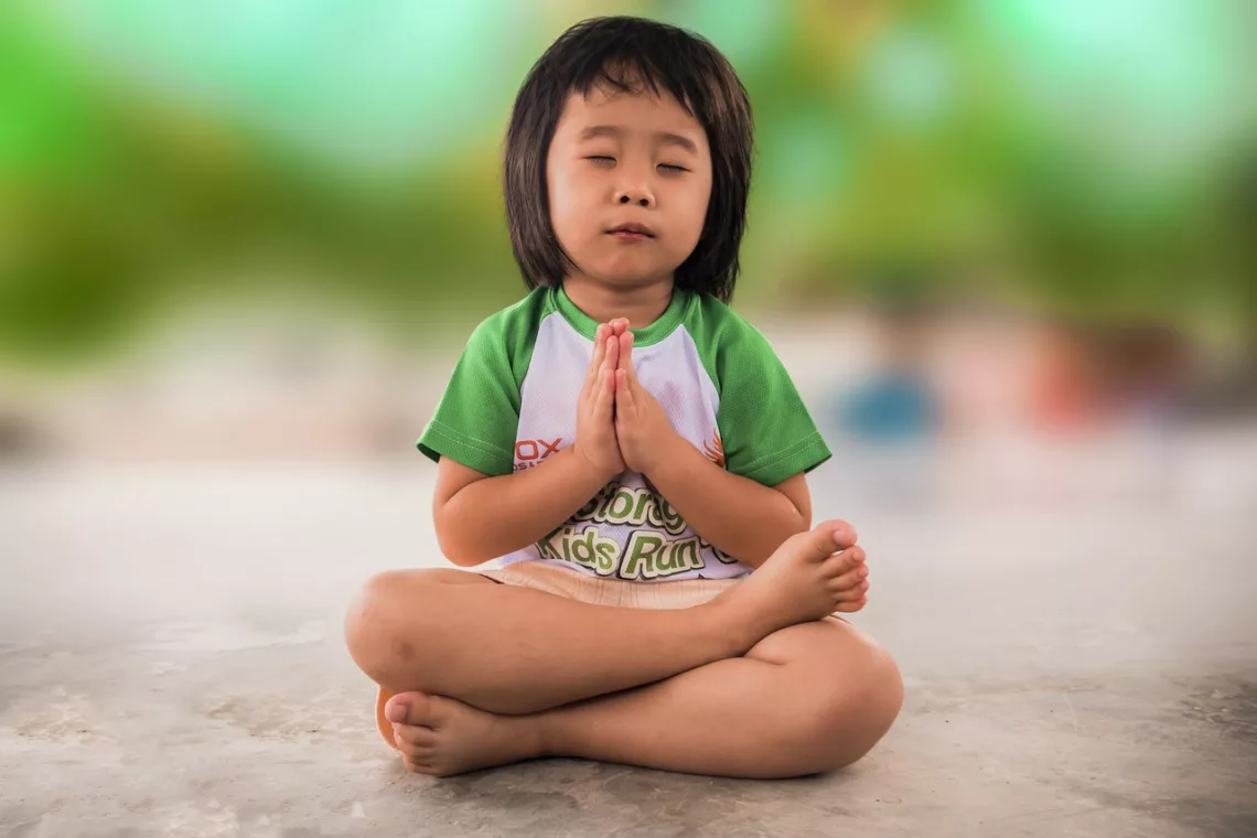 Un petit garçon est assis en position de méditation