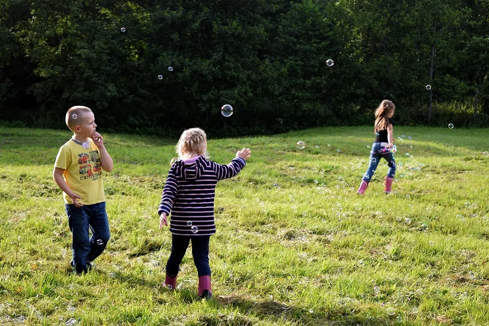 Un groupe d'enfants jouent dans un jardin à faire des bulles