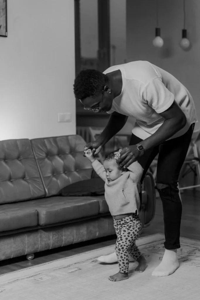 Un papa tient son bébé avec les mains pour lui apprendre à marcher