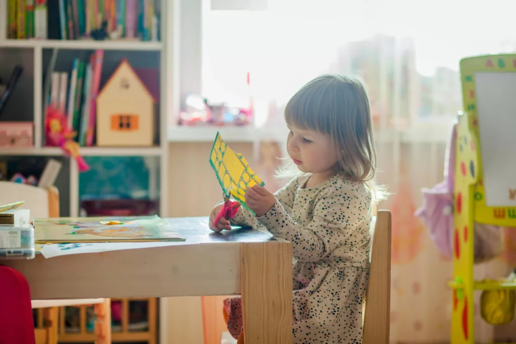 Une petite fille fait du découpage dans sa classe de maternelle