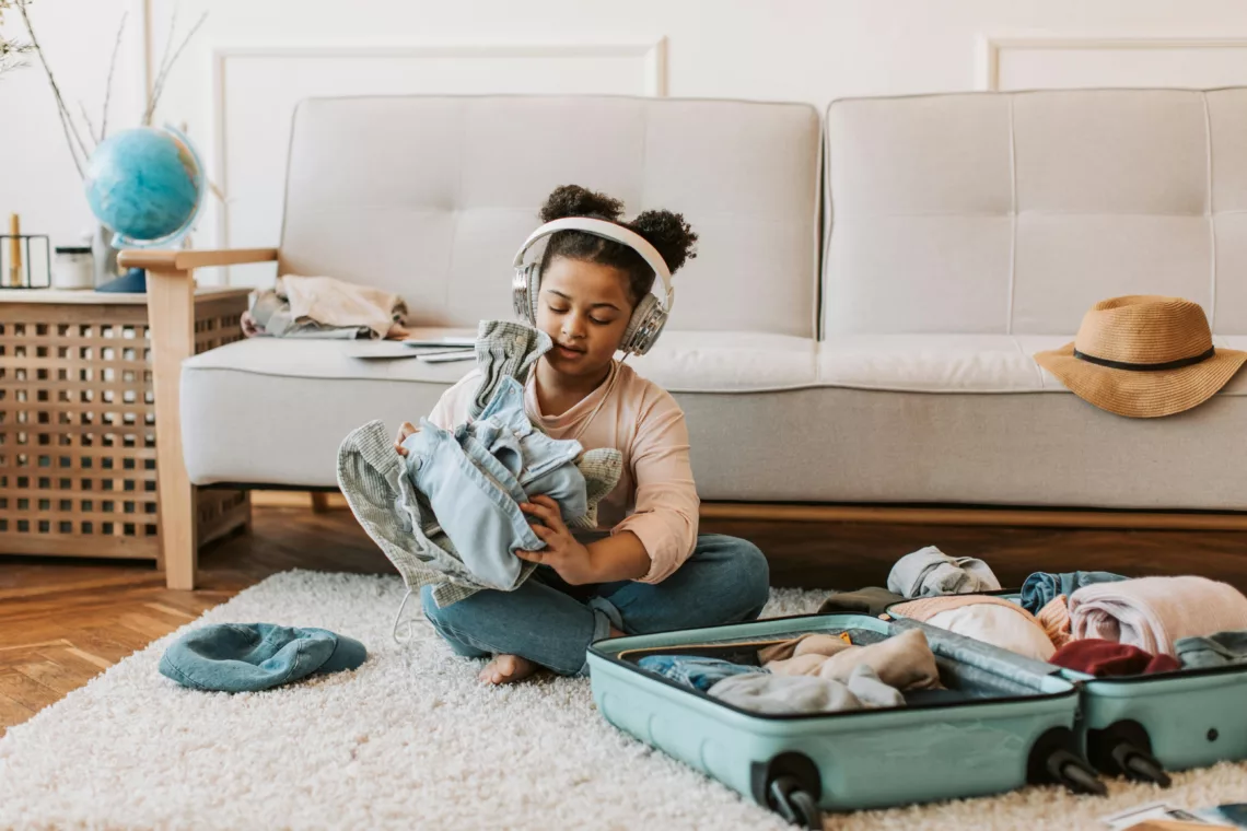 Une petite fille écoute un podcast tout en faisant sa valise