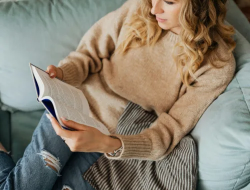 Adulte lisant un livre sur un canapé pour se détendre