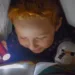 Petit garçon qui lit un livre sous sa couette