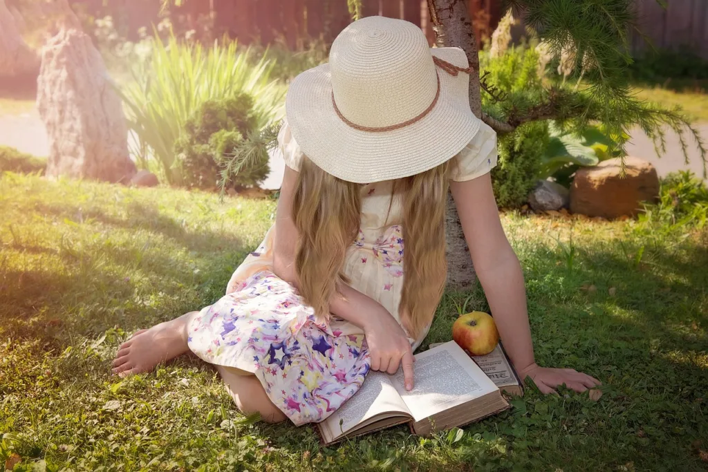 Une jeune fille lit un livre dans un parc