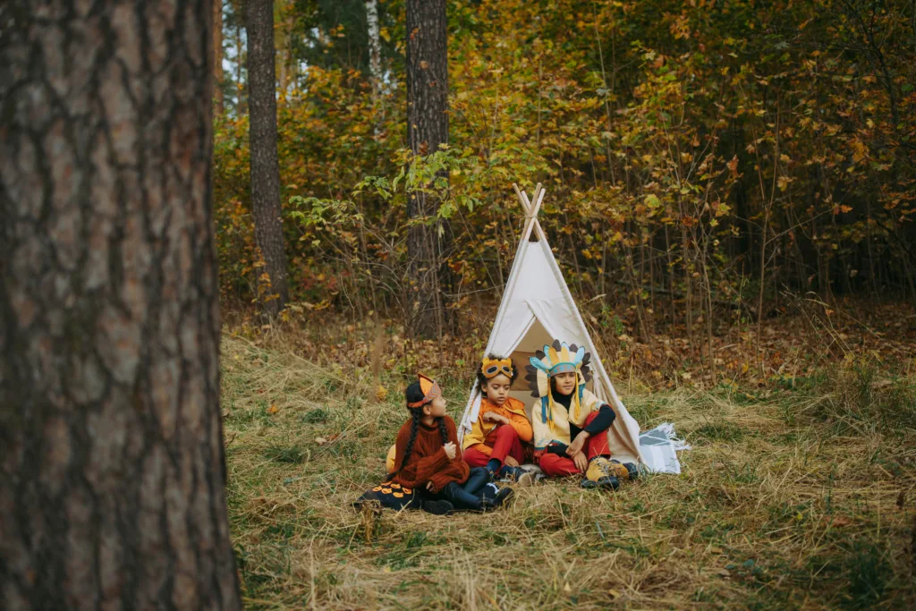 Des enfants sont dans un tipi au milieu de la forêt