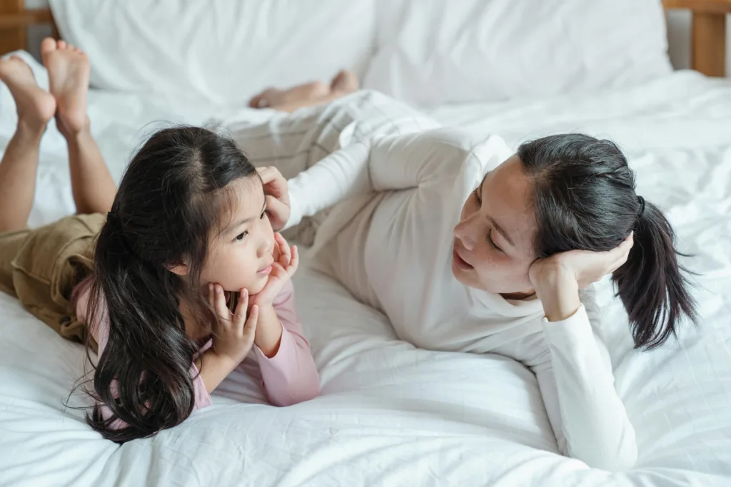 Une maman échange avec sa fille sur son lit