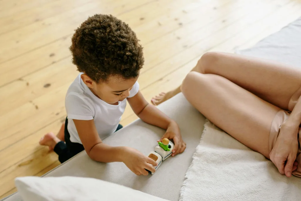 Slow parenting : Un petit garçon joue aux voitures à côté de sa maman