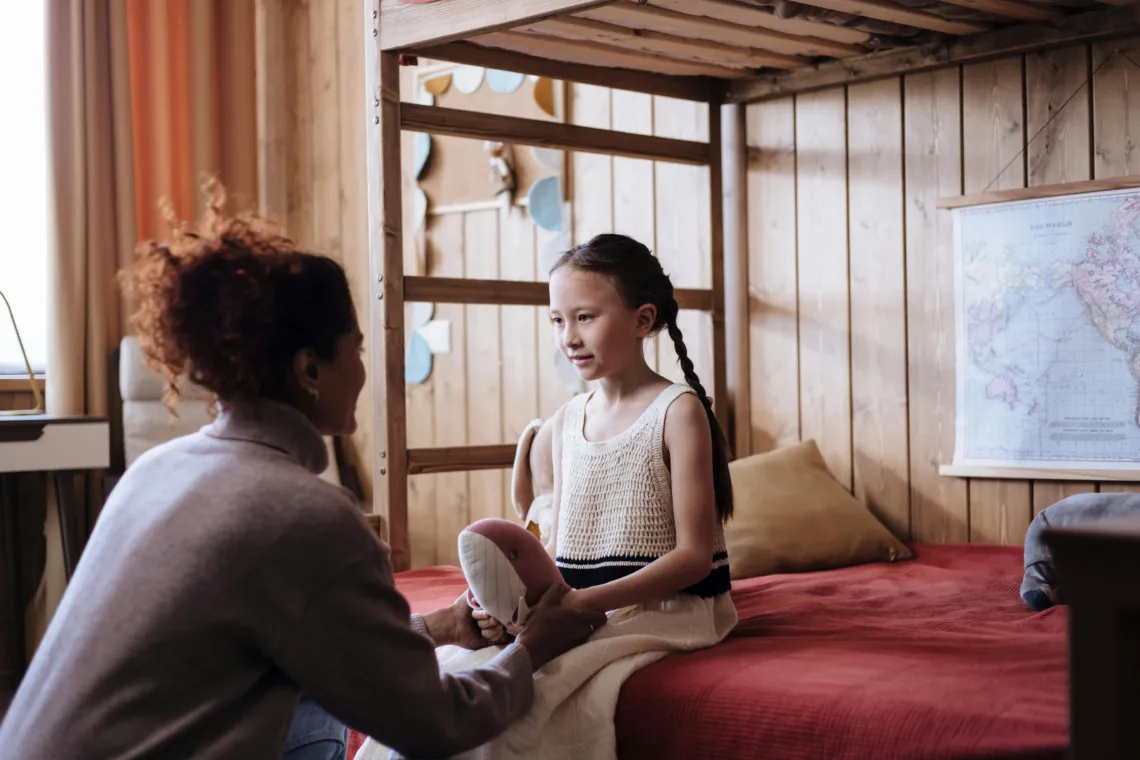 Une maman discute avec sa fille dans sa chambre