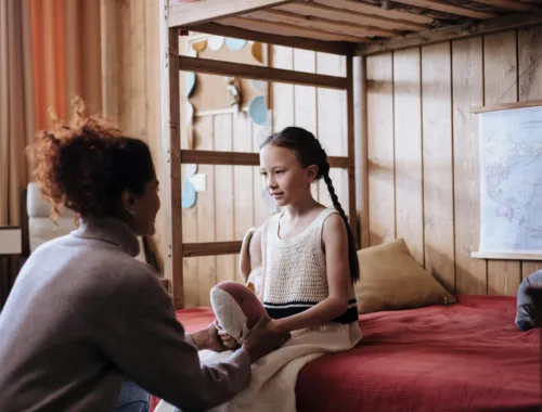 Une maman discute avec sa fille dans sa chambre